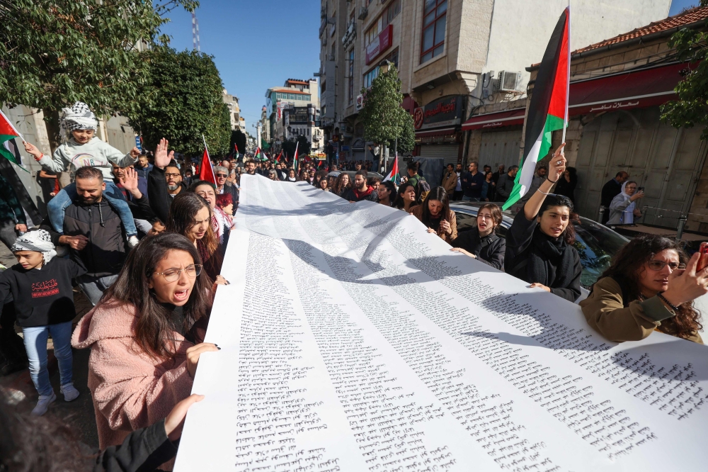 Palestinians carry a list of Gaza victims during a rally amid a general strike in Ramallah city in the occupied West Bank. — AFP 