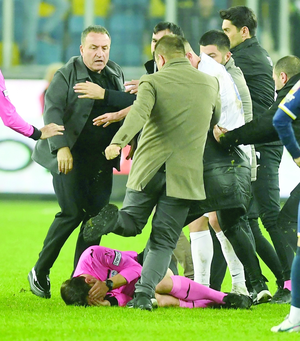 Turkish Referee Halil Umut Meler (ground) cover itself as MKE Ankaragucu's president Faruk Koca (L) attacks him at the end of the Turkish Super Lig football match between MKE Ankaragucu and Caykur Rizespor at Eryaman Stadium in Ankara, on December 11, 2023. 