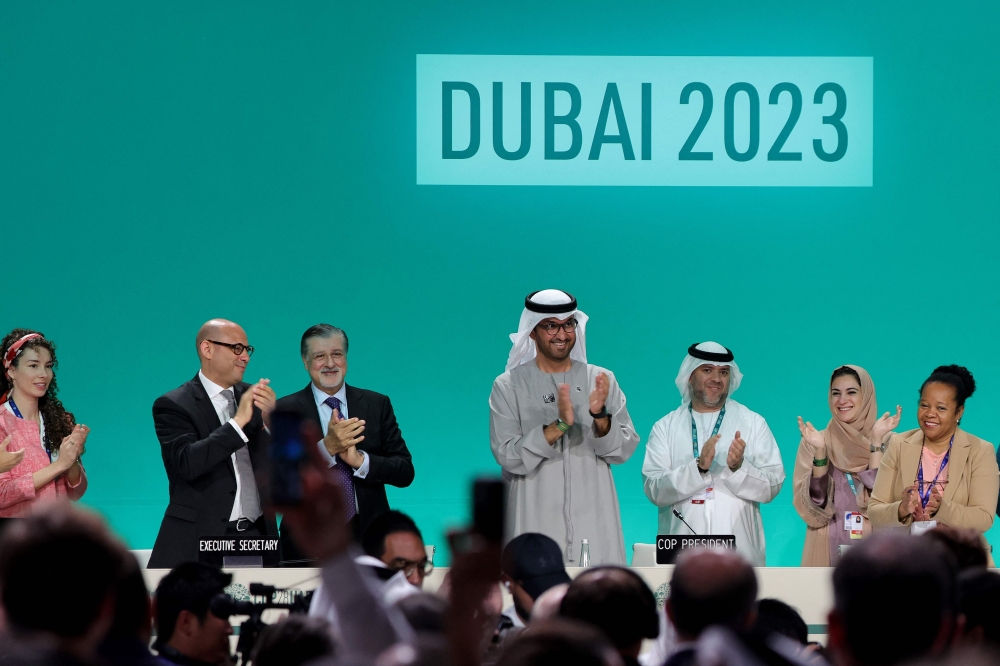 COP28 president Sultan Ahmed Al Jaber (C) applauds among other officials before a plenary session during the United Nations climate summit in Dubai 
