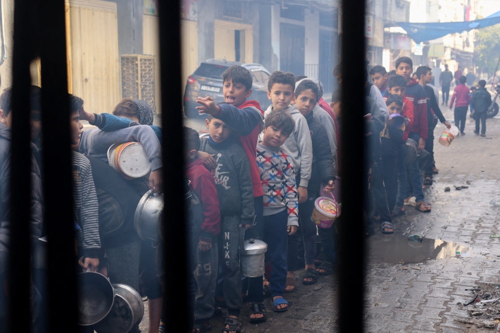Palestinian children queue to receive food cooked by a charity kitchen, amid shortages in food supplies, in Rafah. — Reuters 