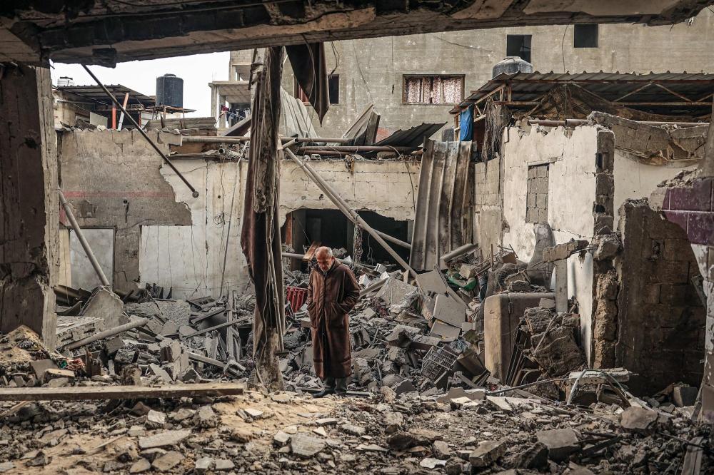 TOPSHOT - A Palestinian man walks amidst debris following Israeli bombardment in Rafah, in the southern Gaza Strip on December 14, 2023, amid ongoing battles between Israel and the Palestinian militant group Hamas. Israeli leaders on December 13, they intend to press ahead with the Gaza Strip war against Hamas, despite coming under increasing international pressure, including from key ally the United States. 
