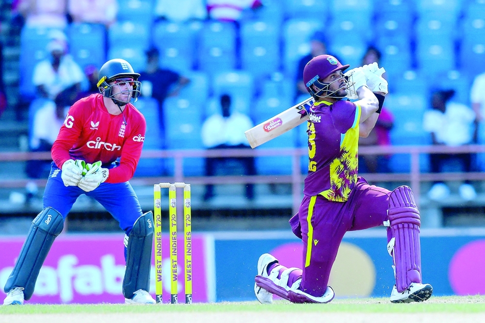 Brandon King (R) of West Indies hits 6 and Jos Buttler (L) of England watch during the 2nd T20I between West Indies and England at Grenada National Cricket Stadium, in St. George's, Grenada, on December 14, 2023.
 (Photo by Randy Brooks / AFP)

