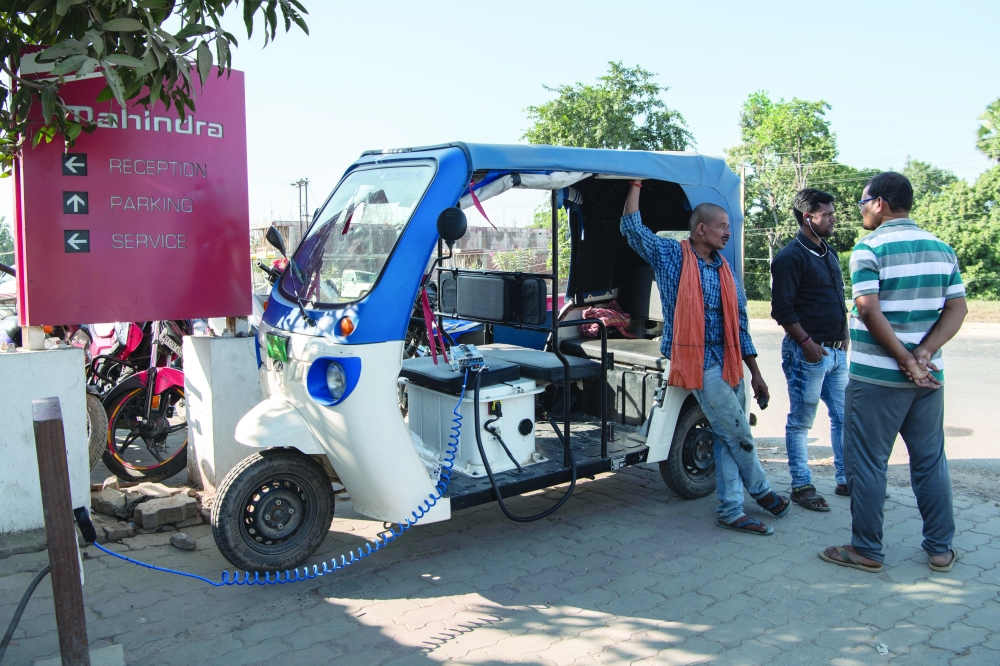 An electric rickshaw driver charges up at a Mahindra showroom in Darbhanga, India.