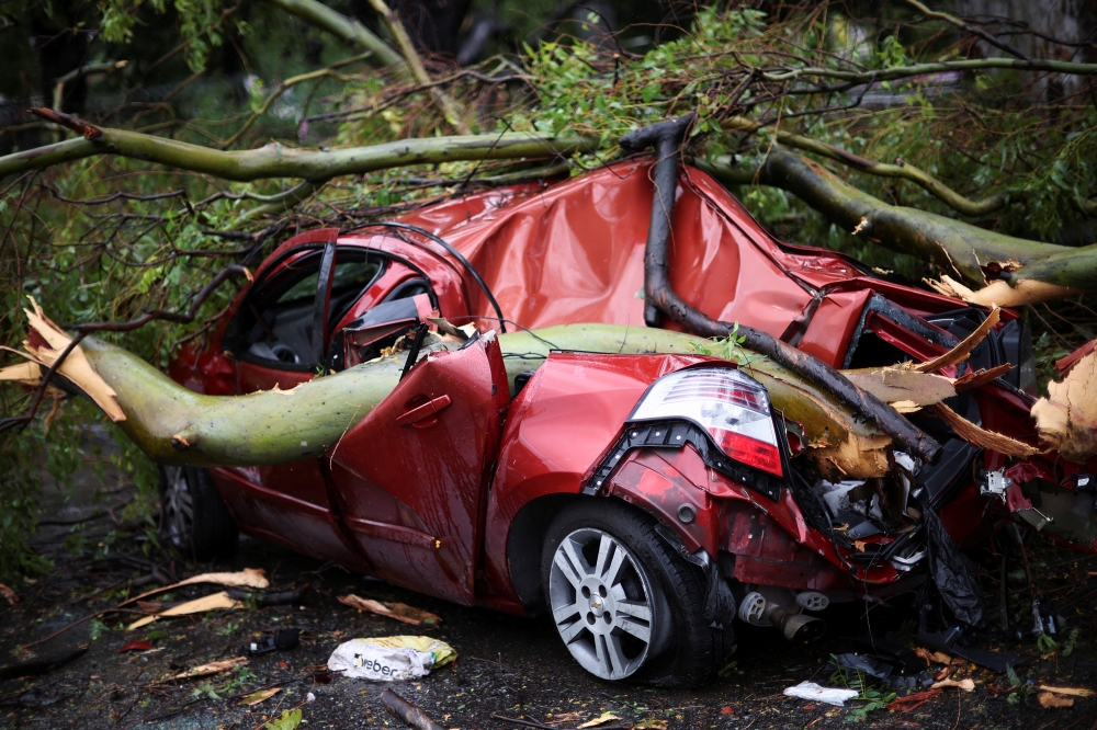 Tree branches lie on top of a damaged car after a severe storm, in Buenos Aires