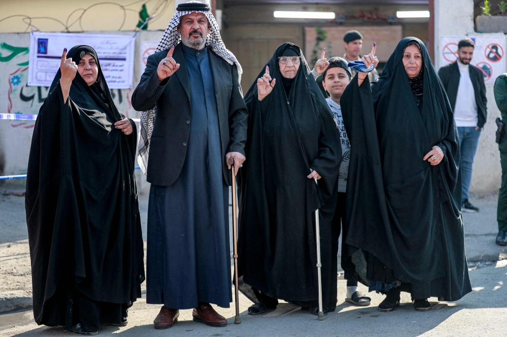 Members of an Iraqi family show their ink-stained fingers after voting in the 2023 Iraqi provincial council elections, outside a polling station in Sadr City in eastern Baghdad. — AFP 