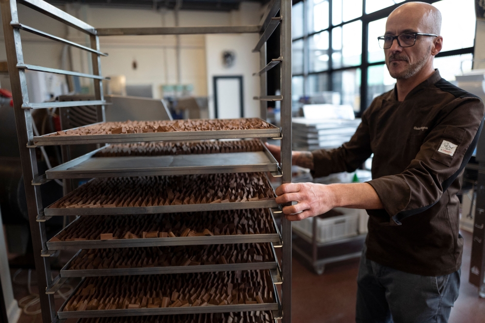 Guido Castagna is pictured in his laboratory where he is making the famous chocolate treat shaped like lingots, the 'Gianduiotto' with cacao, sugar and hazelnut, on December 12, 2023 in Giaveno near Turin, Northwestern Italy.  In Turin, a committee was formed made up of large and small local chocolate producers in order to obtain PGI recognition (Protected Geographical Indication) for one of the most famous products in the area: the gianduiotto. But the Swiss Lindt group, owner of the Caffarel brand, opposes it. (Photo by MARCO BERTORELLO / AFP)

