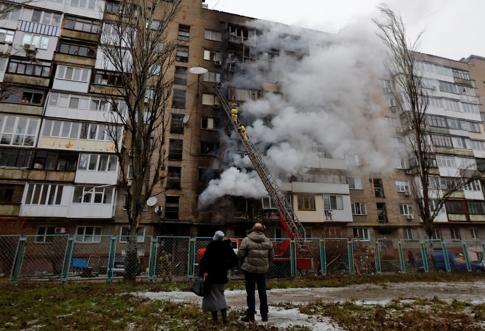 People watch as smoke billows from an apartment building damaged by recent shelling in the course of Russia-Ukraine conflict in Donetsk. — Reuters 