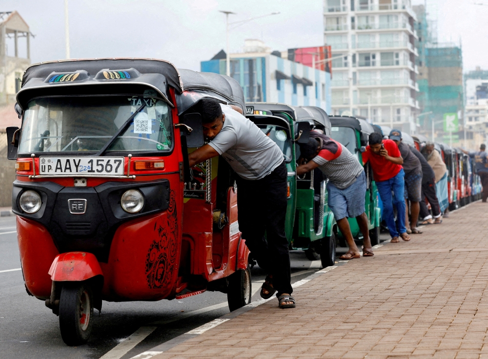 Drivers push auto rickshaws in a line to buy petrol from a fuel station, amid Sri Lanka's economic crisis, in Colombo. — Reuters