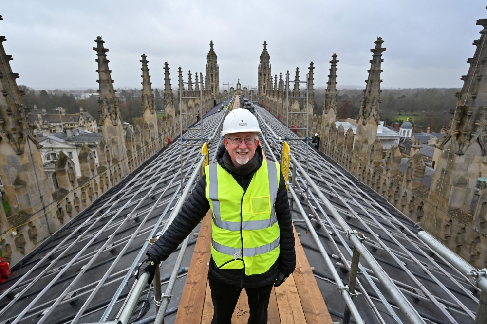 Dean of Chapel at King's College, Stephen Cherry, poses for a photograph as solar panels are installed on the roof of King's College chapel in Cambridge, eastern England on December 13, 2023.  High above the historic streets of Cambridge in eastern England, the installation of solar panels atop King's College Chapel, the world-famous university's most recognisable building, has stirred excitement -- and controversy. (Photo by Justin TALLIS / AFP)


