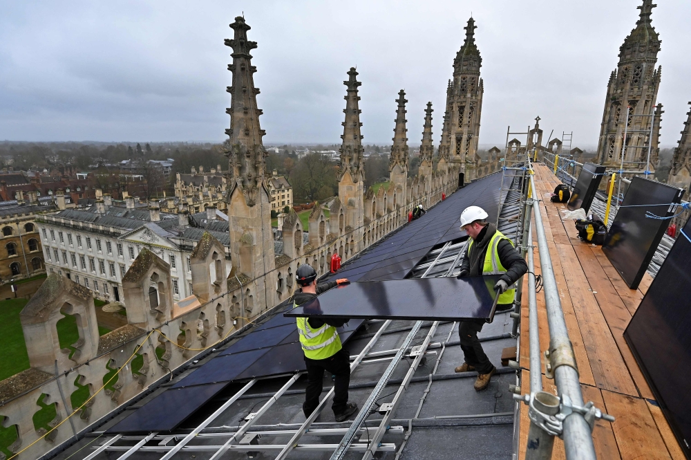 TOPSHOT - Solar panels are installed on the roof of King's College chapel in Cambridge, eastern England on December 13, 2023.  High above the historic streets of Cambridge in eastern England, the installation of solar panels atop King's College Chapel, the world-famous university's most recognisable building, has stirred excitement -- and controversy. (Photo by Justin TALLIS / AFP)

