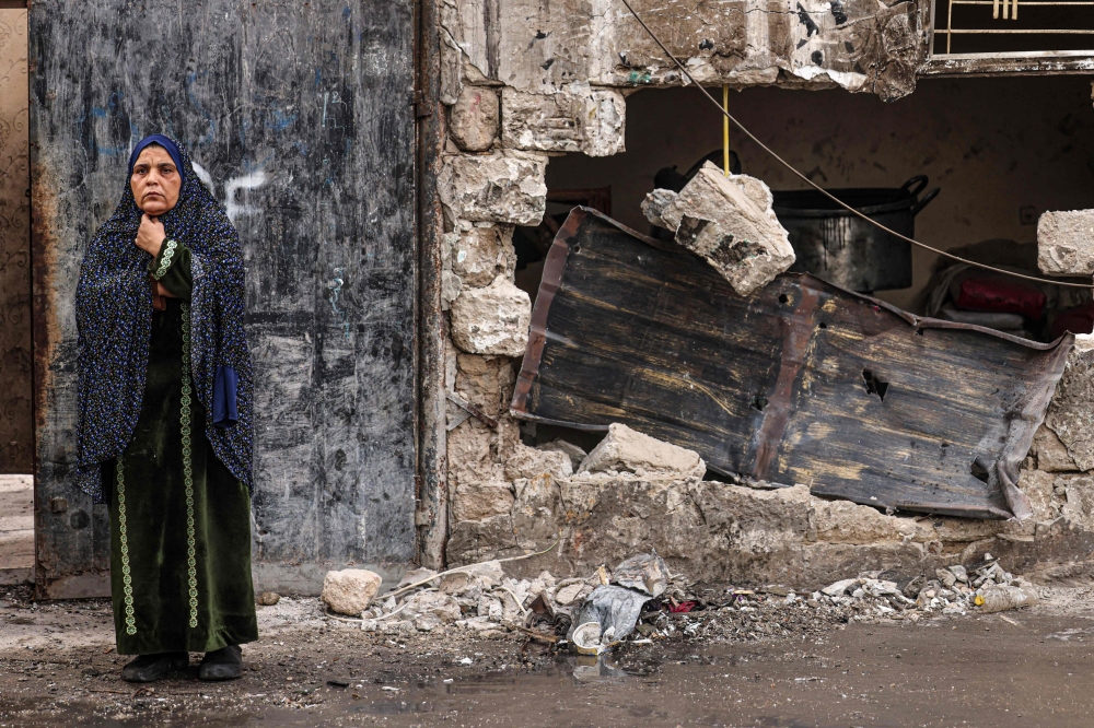 A woman stands in front of a house destroyed in Israeli bombardment in Rafah, in the southern Gaza Strip. - AFP

