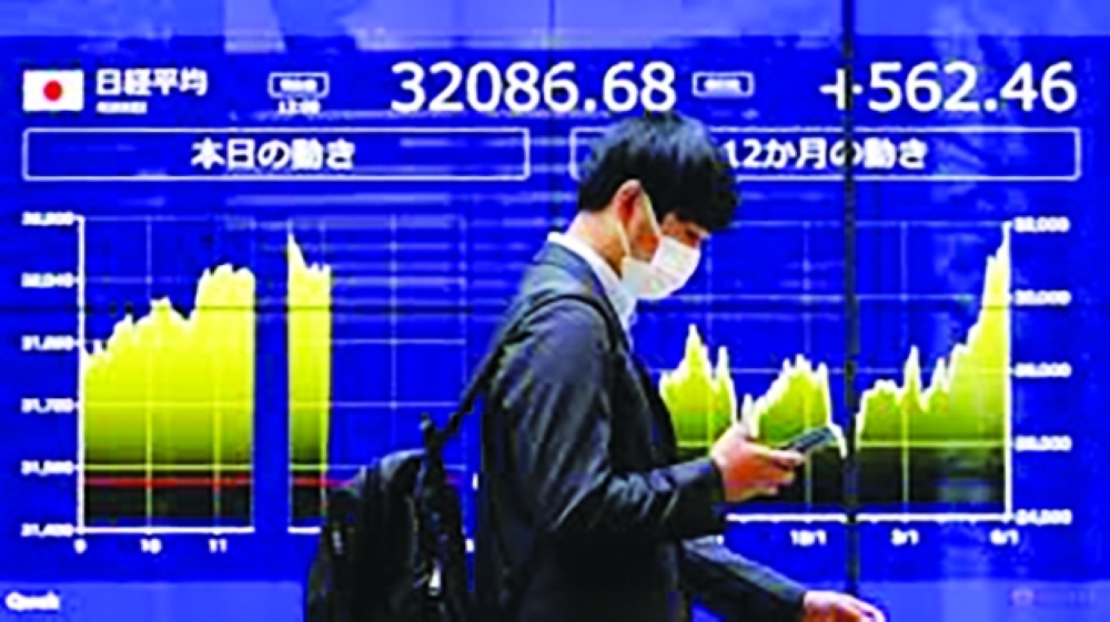 A man walks past an electric monitor displaying Japan's Nikkei share average and recent movements, outside a bank in Tokyo, Japan, June 5, 2023. REUTERS