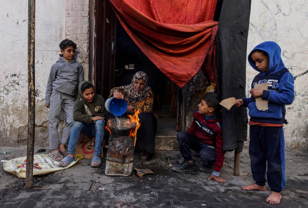 A Palestinian woman makes food outside a house in the southern Gaza Strip 