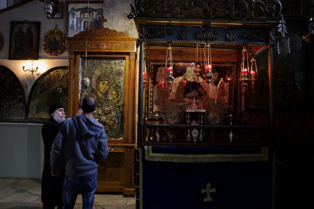 Members of clergy change oil in a lamp in the Church of the Nativity, in Bethlehem. — Reuters