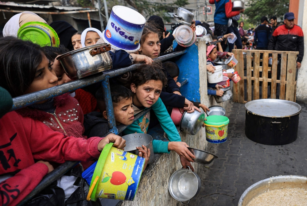 Palestinian children wait to collect food at a donation point in a refugee camp in Rafah in the southern Gaza Strip. — AFP 