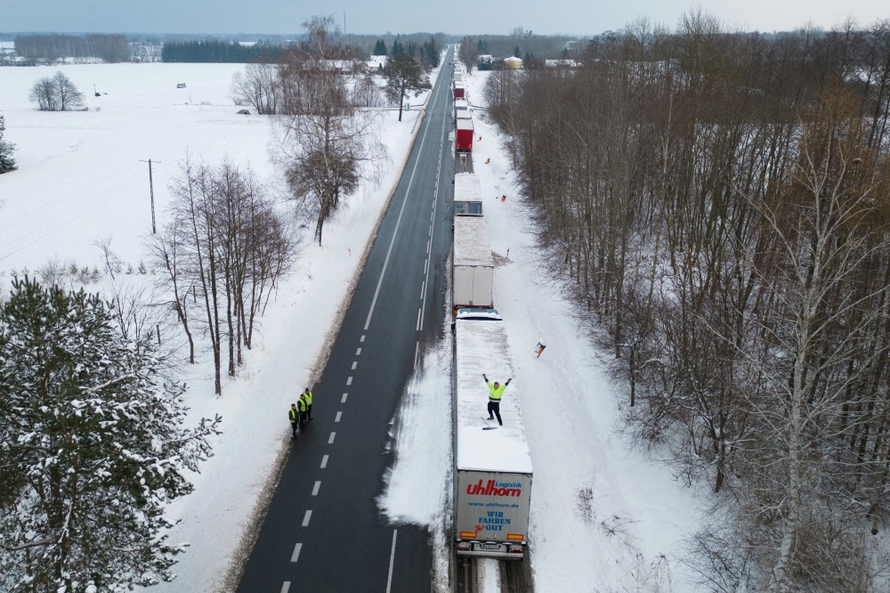 A truck driver from Ukraine waves from his truck roof while waiting in a long queue to cross the Polish-Ukrainian border at the Dorohusk-Jagodzin crossing, in Okopy, Poland. — Reuters