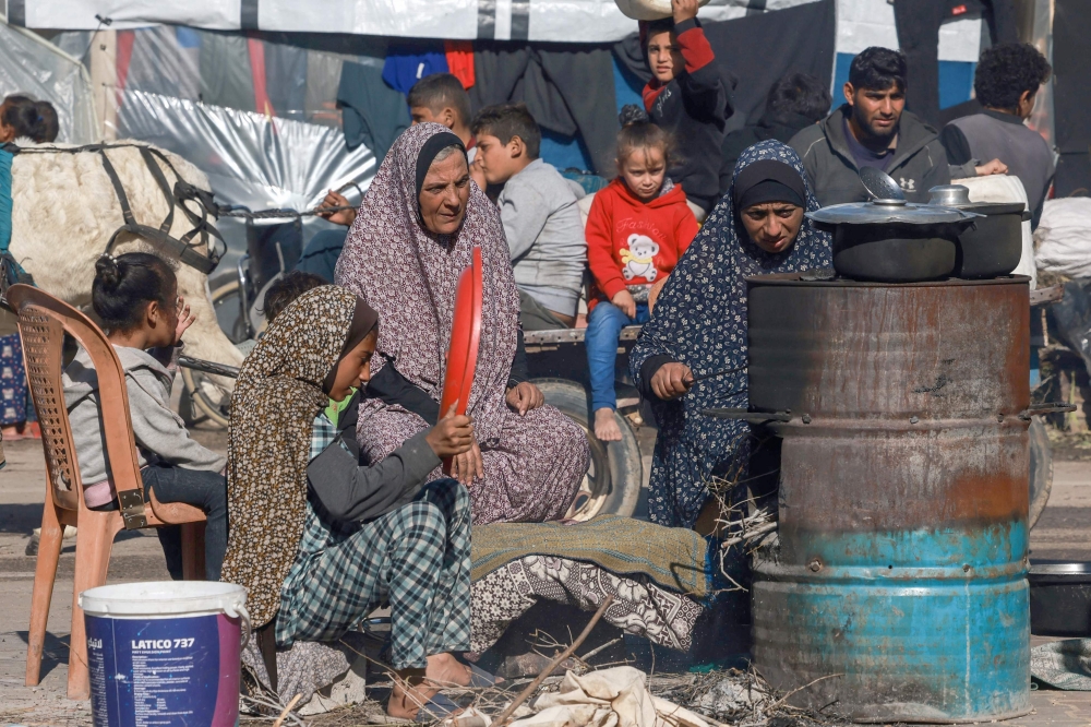 Displaced Palestinians cook in a makeshift outdoor kitchen near their tent in Rafah in the southern Gaza Strip. — AFP 