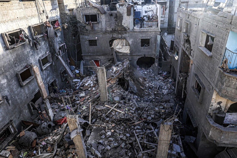 People inspect the rubble of a building destroyed by Israeli bombardment in Rafah. — AFP 