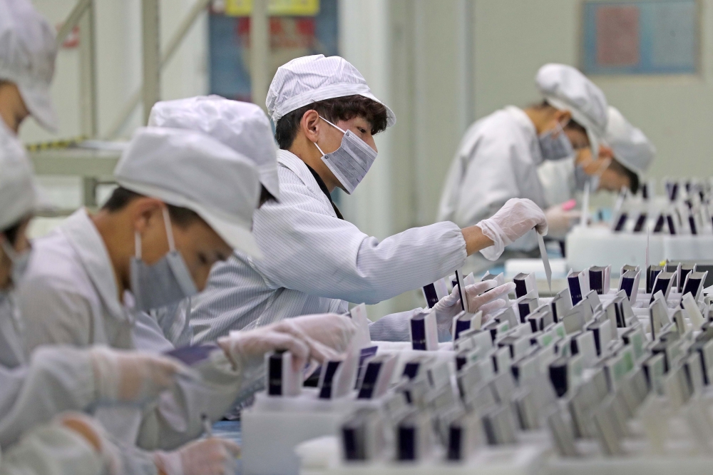 Workers are seen at a production line manufacturing solar photovoltaic components at a factory in Huzhou, Zhejiang, China. — Reuters