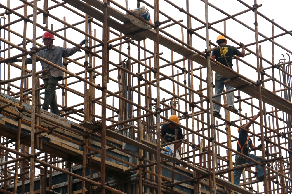 Men work on the scaffolding at a construction site of Hebei Zongheng Iron and Steel plant inside the Tangshan Fengnan Economic Development Zone, Hebei, China. — Reuters