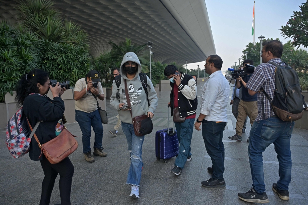 Media representatives take pictures of passengers arriving from France at the airport in Mumbai. - AFP

