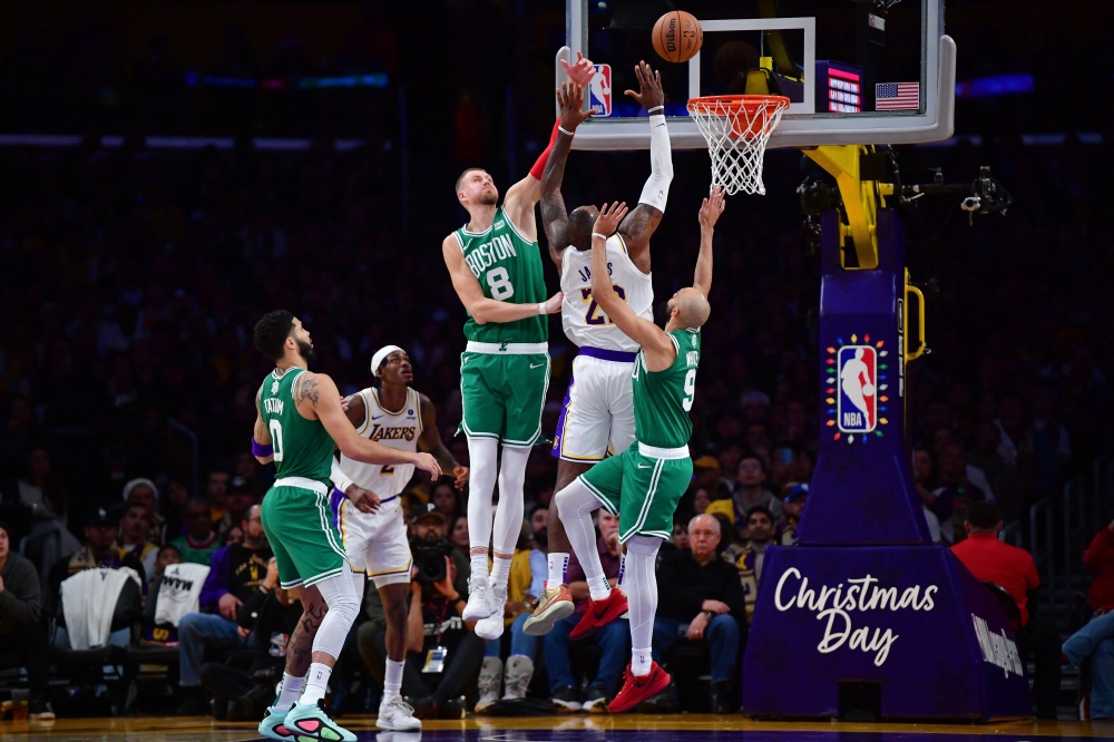 Dec 25, 2023; Los Angeles, California, USA; Boston Celtics center Kristaps Porzingis (8) and guard Derrick White (9) defend against Los Angeles Lakers forward LeBron James (23) during the second half at Crypto.com Arena. Mandatory Credit: Gary A. Vasquez-USA TODAY Sports
