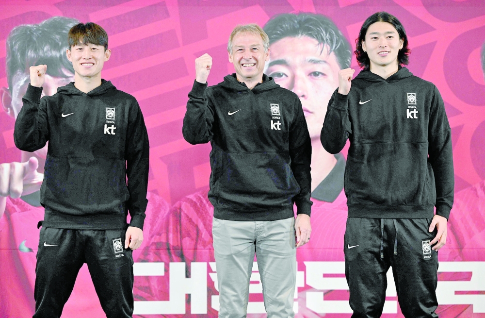 South Korea's national football team head coach Jurgen Klinsmann (C) poses with his players Cho Gue-sung (R) and Lee Jae-sung (L) during a press conference to announce the South Korean squad for the Asian Cup in Seoul on December 28, 2023.  (Photo by Jung Yeon-je / AFP)