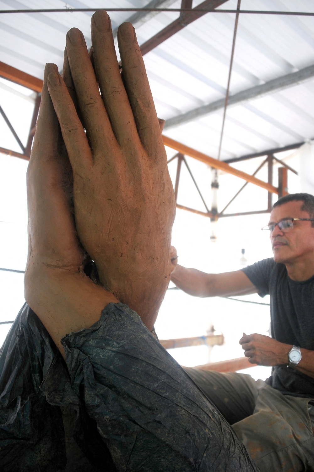 Picture taken on August 25, 2023, of Colombian artist Yino Marquez working in a statue of Colombian singer Shakira in Barranquilla, Colombia. Arms interlocked high, belly exposed, and torso folded to one side anticipate Shakira's iconic hip movement, immortalized on Tuesday in a 6.5-meter-high statue in the Colombian port city of Barranquilla, where she grew up. (Photo by Jesus RICO / AFP)


