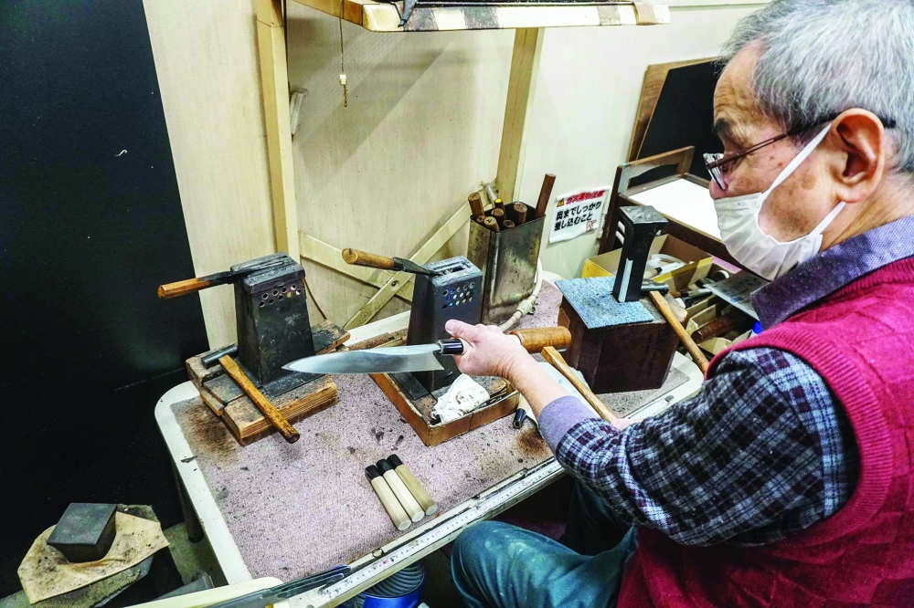 This photo taken on November 14, 2023 shows a handle being attached to a "gyuto", the Japanese equivalent to a western chef痴 knife, at the Yamawaki Cutlery in the city of Sakai, Osaka prefecture. Knife makers can spend an entire day perfecting a single piece. The metal is heated in until malleable and then hammered -- a process repeated several times -- before being shaped, quenched in oil or water and left to cool. 