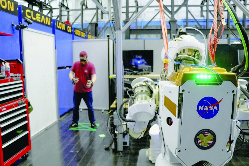 Nasa software engineer Ian Chase controls the humanoid robot Valkyrie with a VR headset and controllers at the Johnson Space Center in Houston. - Reuters