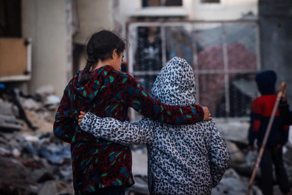 TOPSHOT - Children embrace as people inspect the damage following Israeli bombardment in Rafah on the southern Gaza Strip on December 29, 2023, amid the ongoing battles between Israel and the Palestinian militant group hamas. 