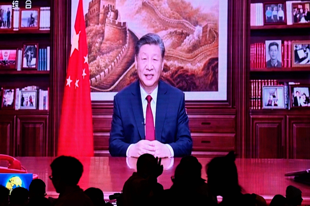 TOPSHOT - People have their dinner at a restaurant as a screen broadcasts China's President Xi Jinping while delivering his New Year's speech in Beijing on December 31, 2023. 