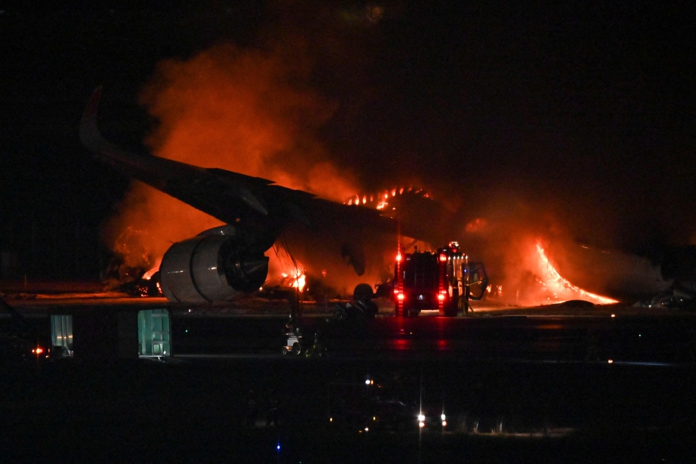 A Japan Airlines (JAL) passenger plane is seen on fire on the tarmac at Tokyo International Airport at Haneda 