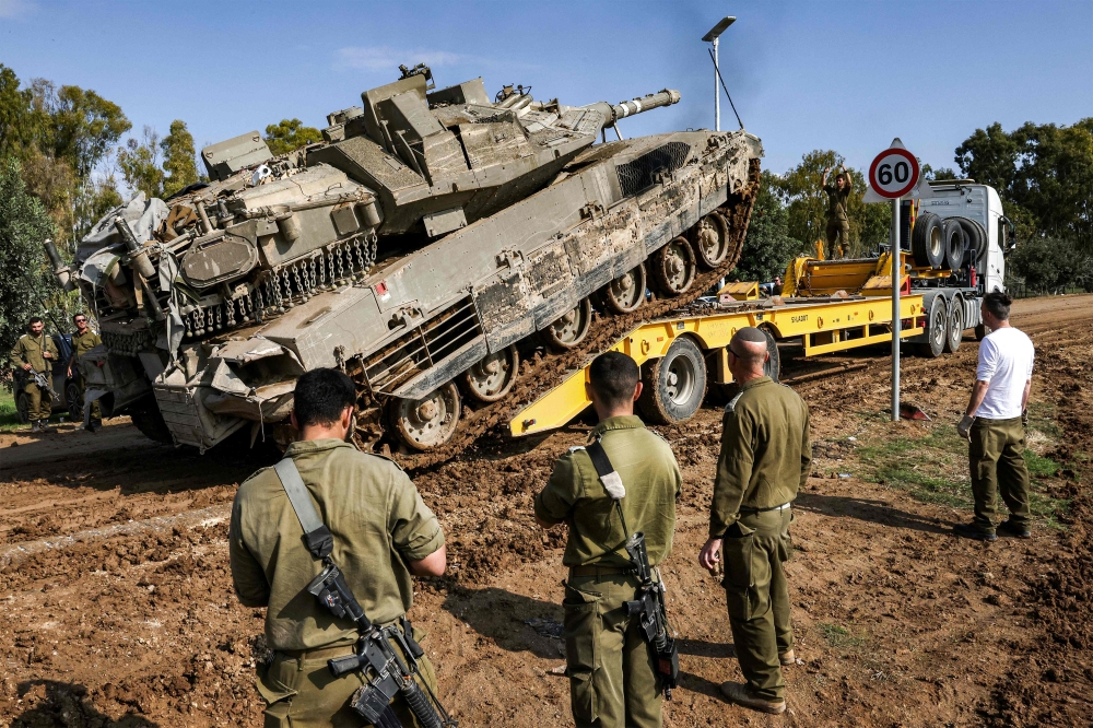 An Israeli battle tank rolls onto a trailer truck at a position along the border with the Gaza Strip and southern Israel. — AFP 