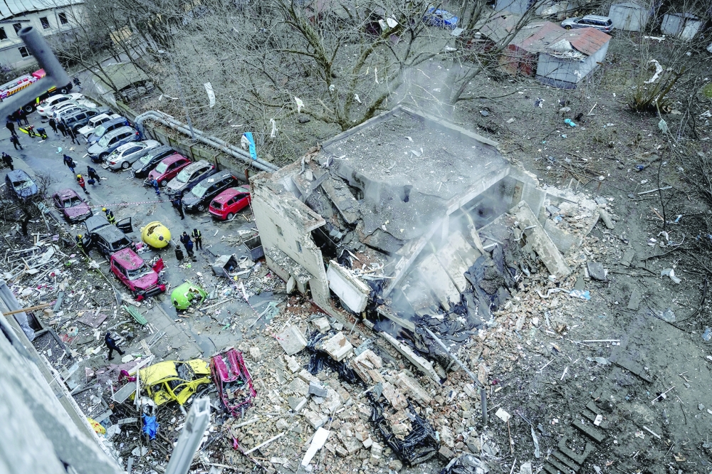 People stand next to destroyed cars at a site of a Russian missile strike, amid ongoing conflict, in Kyiv, Ukraine. — Reuters