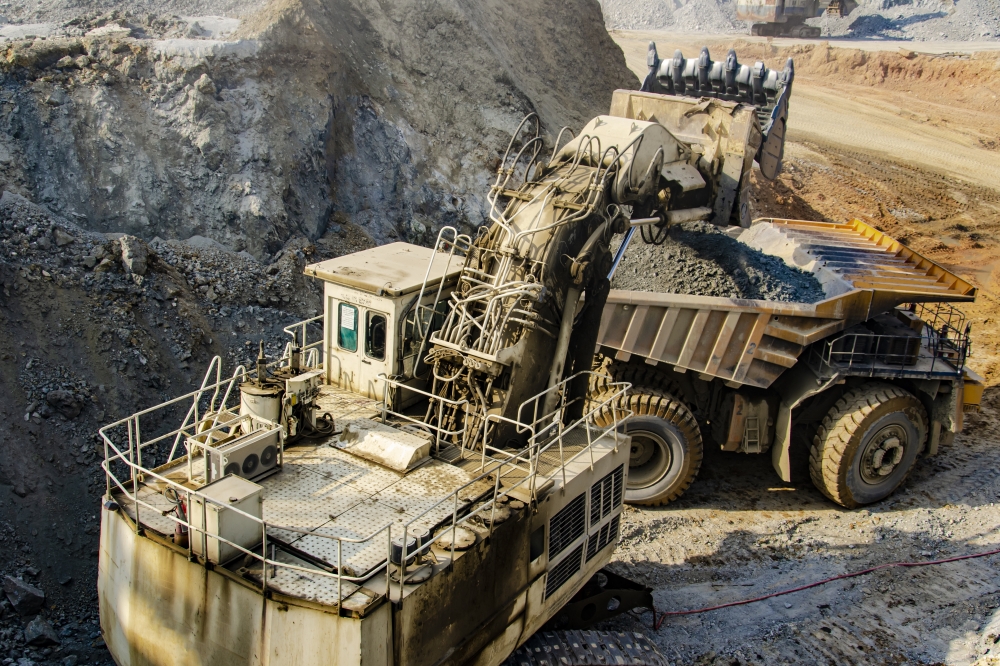 Excavator loading big dump truck in open pit
