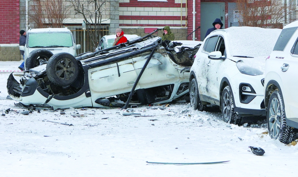 People stand next to damaged cars in a courtyard of a multi-storey apartment building following what local authorities say was a Ukrainian military strike in the city of Belgorod. - Reuters