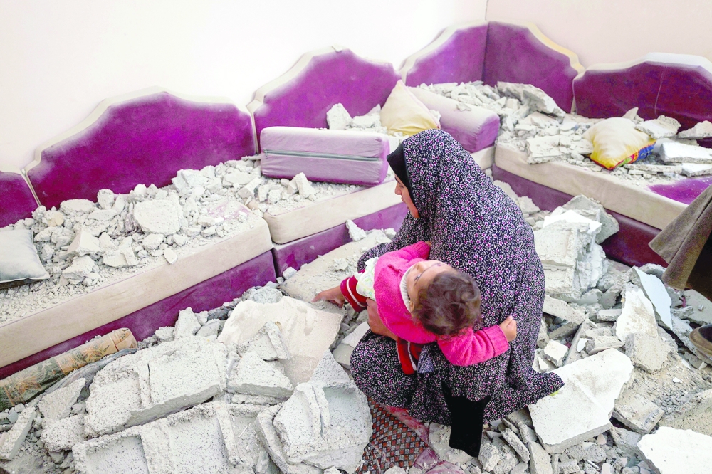 A woman holds a child as she inspects the damage following Israeli bombardment in Rafah on Friday. — AFP