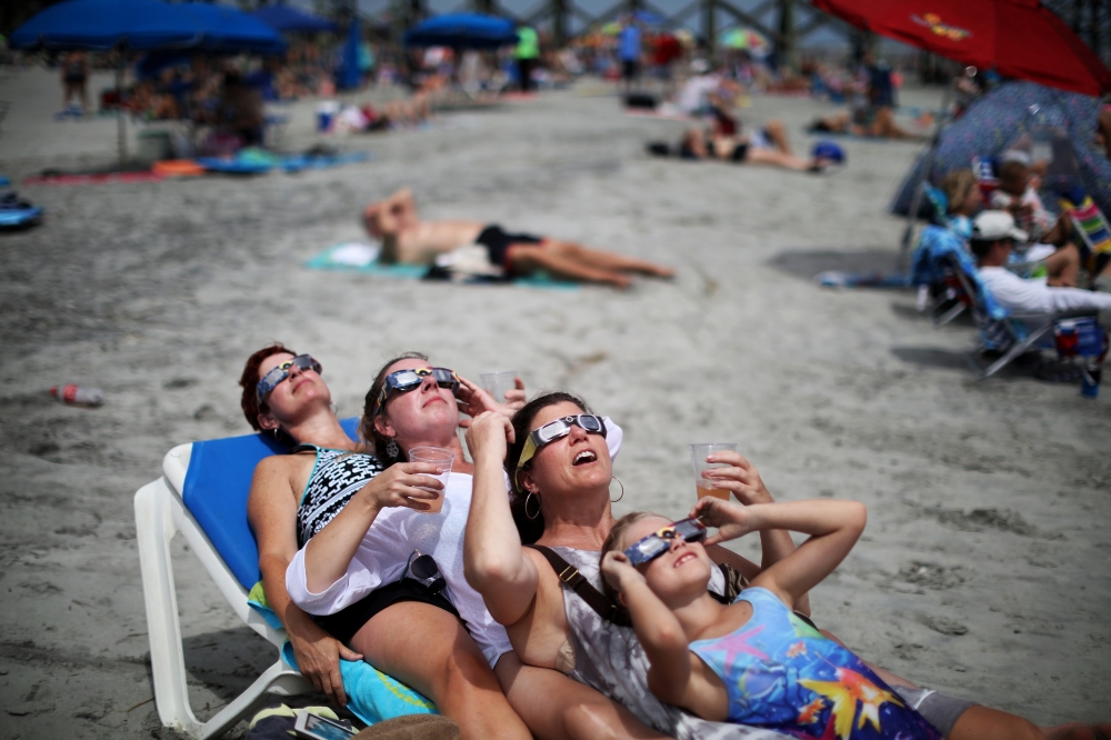 A group of beachgoers view the solar eclipse in Folly Beach, S.C., Aug. 21, 2017. (Travis Dove/The New York Times)