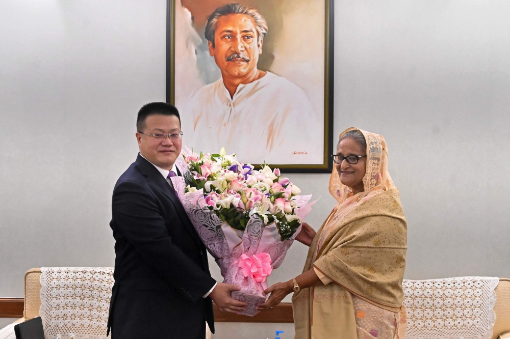Chinese ambassador to Bangladesh Yao Wen (L) congratulates Bangladesh's Prime Minister Sheikh Hasina with a floral bouquet in Dhaka