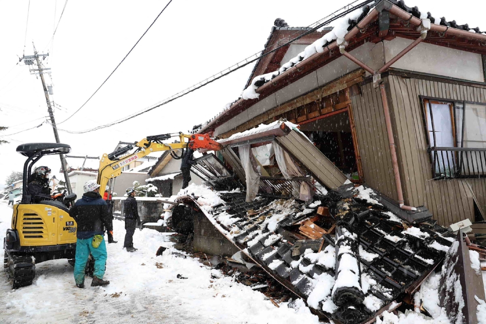 This photo shows volunteers demolishing a partially collapsed house in the city of Suzu, Ishikawa prefecture. — AFP 