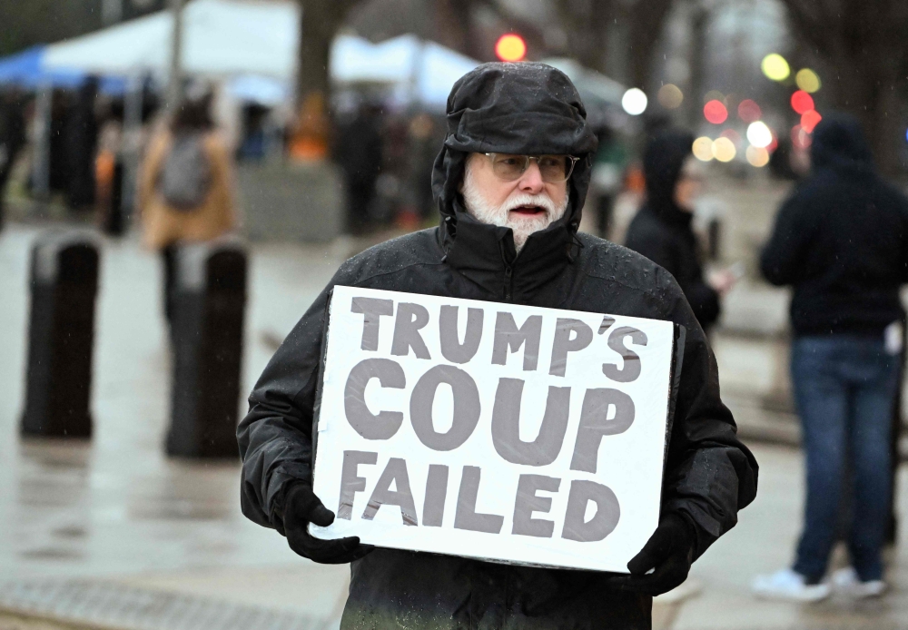 A lone protester holds a sign outside the E. Barrett Prettyman US Courthouse in Washington, DC on on Tuesday. — AFP