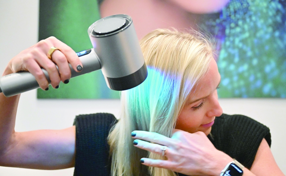 Emily Stephens demonstrates usage of L'Oreal's Airlight Pro hairdryer, which uses patented infrared light technology, at the 2024 Consumer Electronics Show in Las Vegas. - AFP 