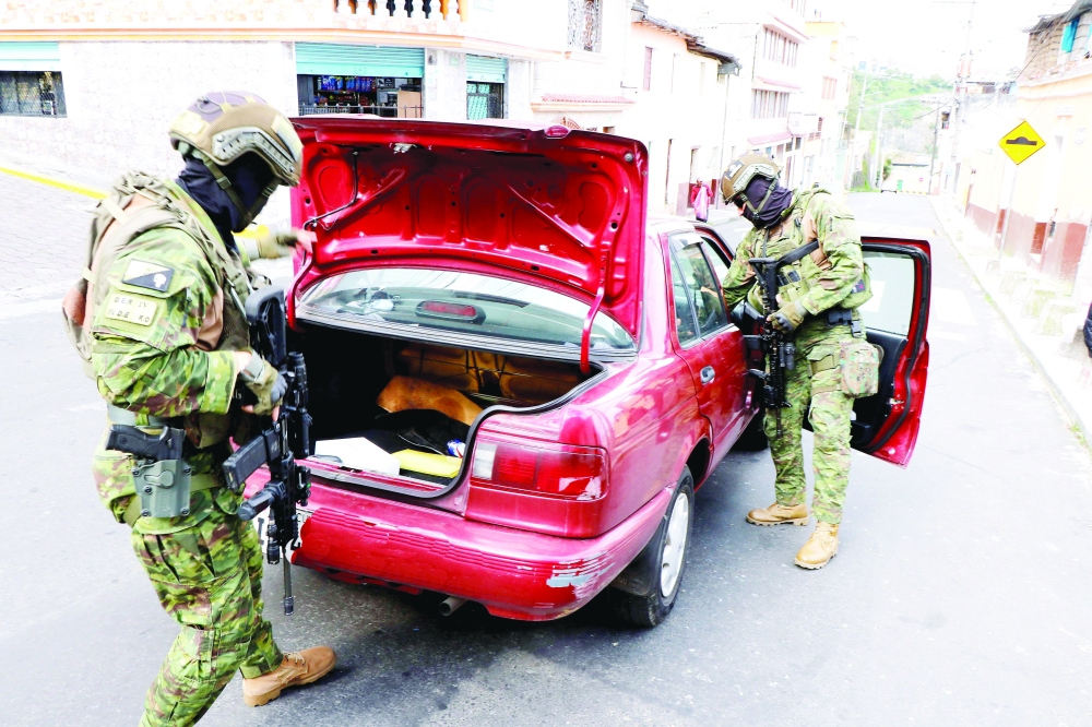 Members of the Armed Forces check a car during an operation to protect civil security in Quito. — AFP