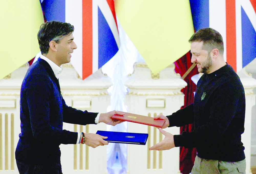 British Prime Minister Rishi Sunak exchanges documents with Ukrainian President Volodymyr Zelensky in Kyiv. - Reuters