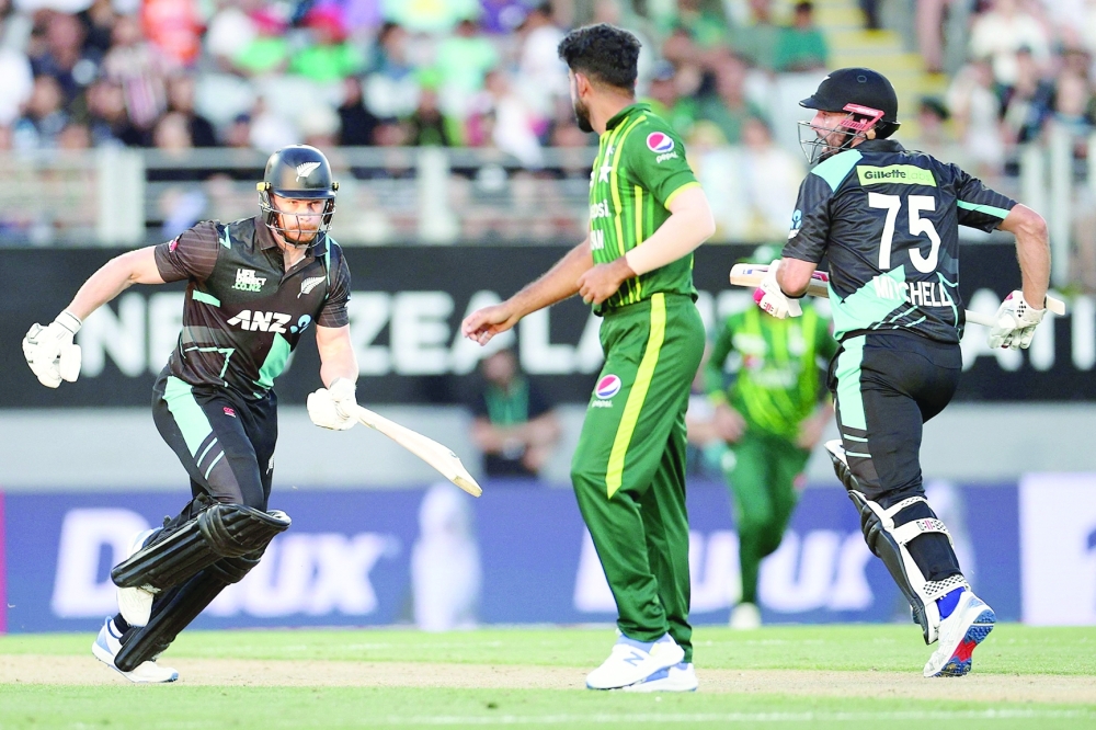 New Zealand's Glenn Phillips (L) and Daryl Mitchell run between the wickets during the first Twenty20 international cricket match between New Zealand and Pakistan at Eden Park in Auckland on January 12, 2024.  (Photo by DAVID ROWLAND / AFP)

