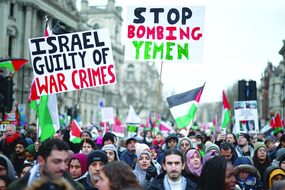 Activists and supporters wave flags and carry placards, including a 'Stop Bombing Yemen' sign, during a National March for Palestine in central London on Saturday. - AFP