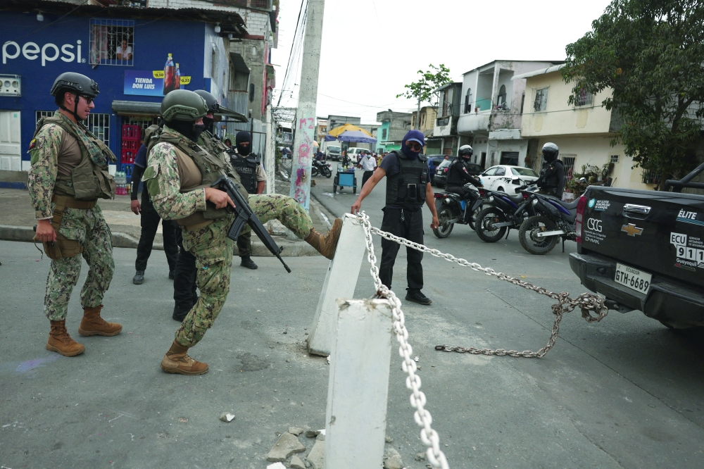 A soldier kicks a concrete pole to remove it while patrolling, amid the ongoing wave of violence around the nation, in Guayaquil, Ecuador. — Reuters
