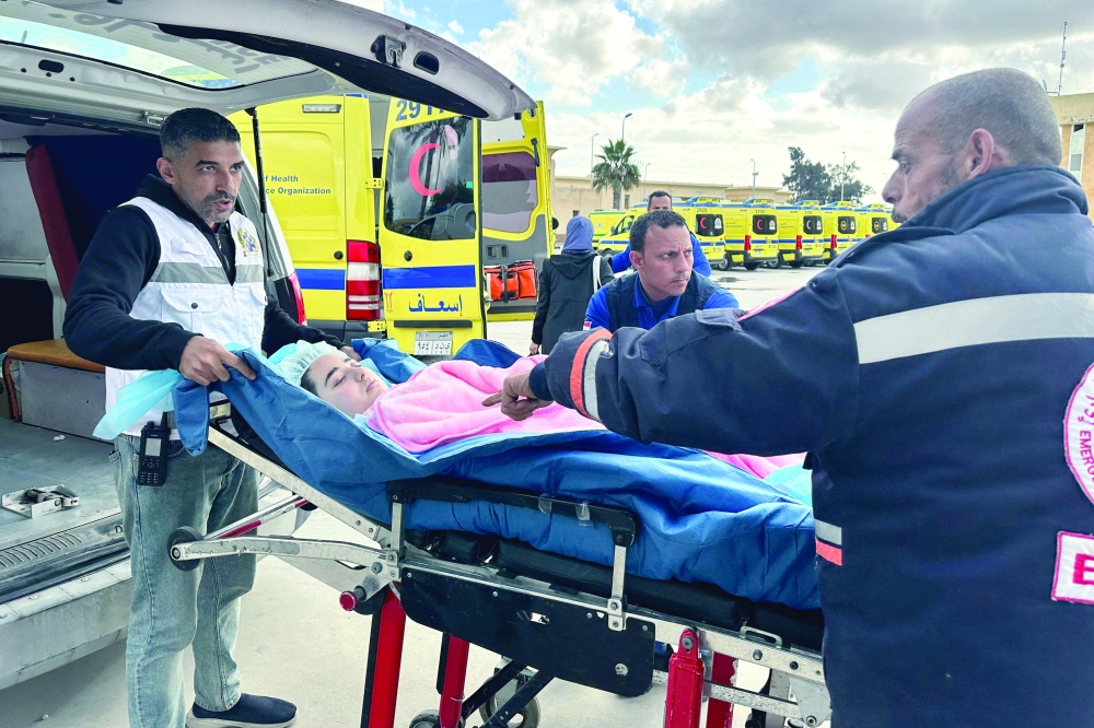An injured Palestinian child is transferred by Egyptian paramedics into an ambulance, after being allowed to be evacuated from the Gaza Strip. — AFP 