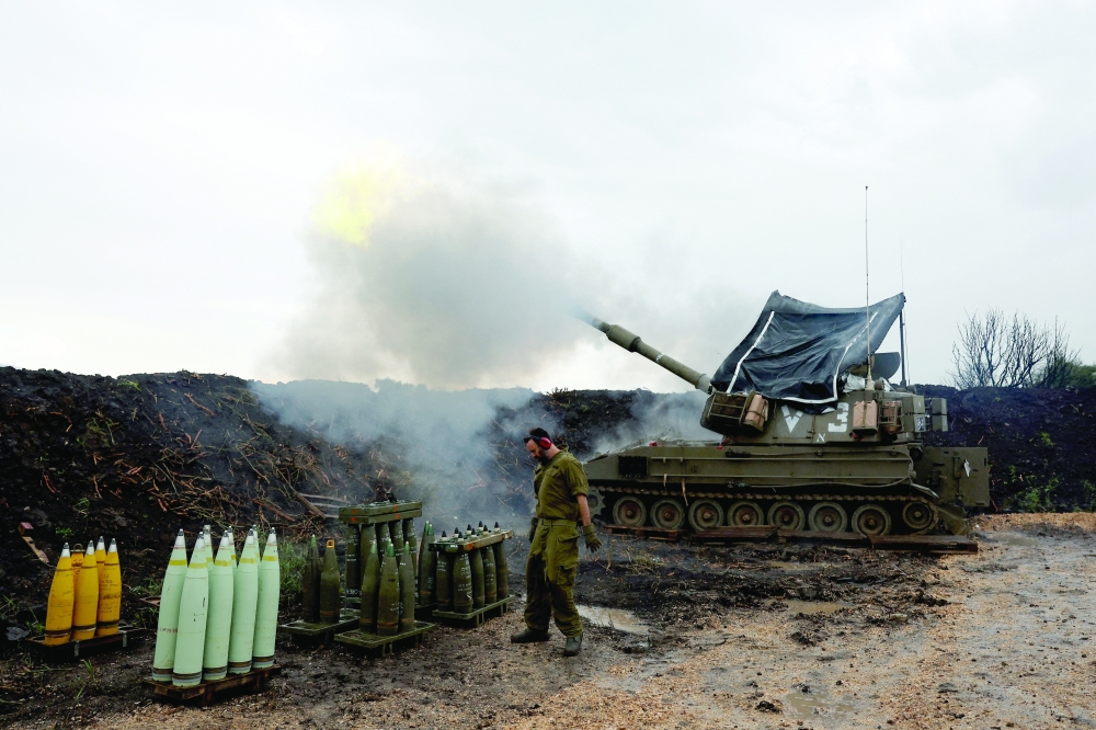 An Israeli soldier stands by, as a mobile artillery unit fires, near the Israel-Lebanon border. — Reuters